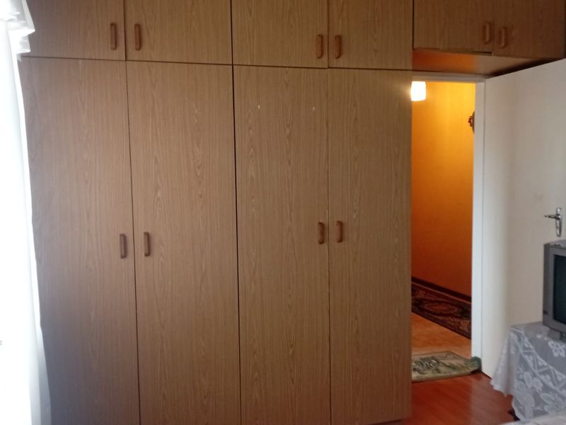 Bedroom featuring extensive floor-to-ceiling built-in wooden cabinetry, laminate flooring, and a ceiling fan, providing ample storage space.