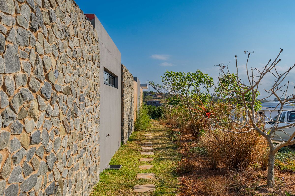 A side garden path featuring stone cladding on the exterior wall, a stepped stone walkway, and established landscaping.