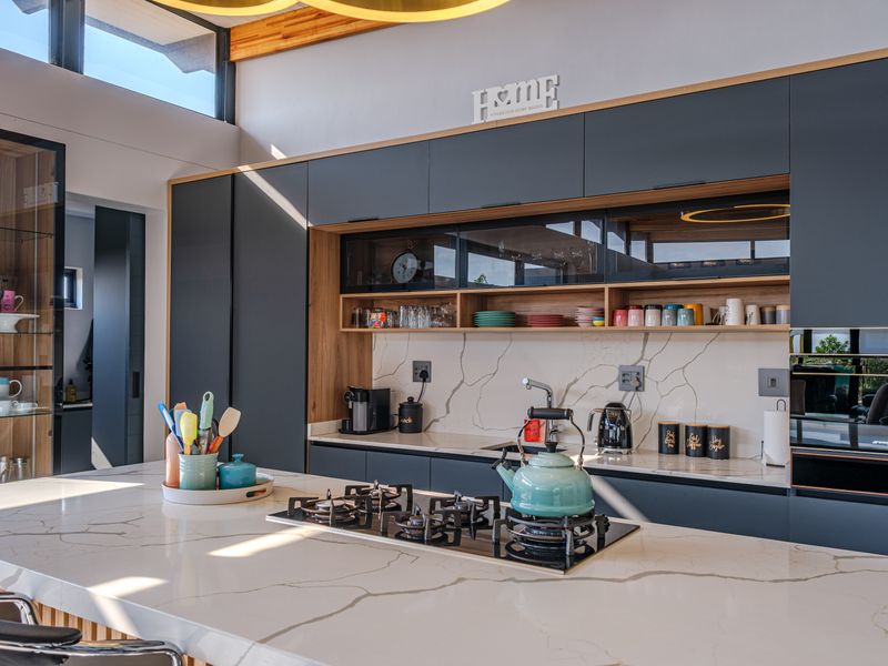 Modern kitchen featuring high-end cabinetry, quartz countertops with marble-look splashback, integrated gas hob, and clerestory windows providing ample natural light.