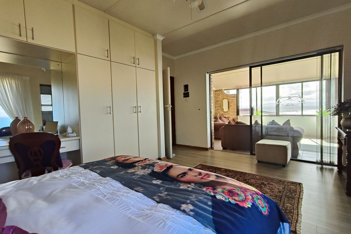 Spacious bedroom featuring extensive built-in cabinetry, laminate flooring, and large sliding glass doors providing direct access to an outdoor patio area.