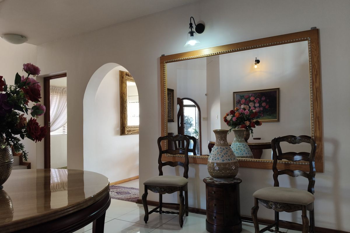 A well-maintained living area featuring a large wall-mounted mirror, elegant archway transition, and polished tiled flooring.