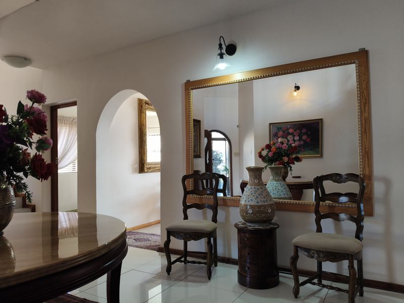 A well-maintained living area featuring a large wall-mounted mirror, elegant archway transition, and polished tiled flooring.