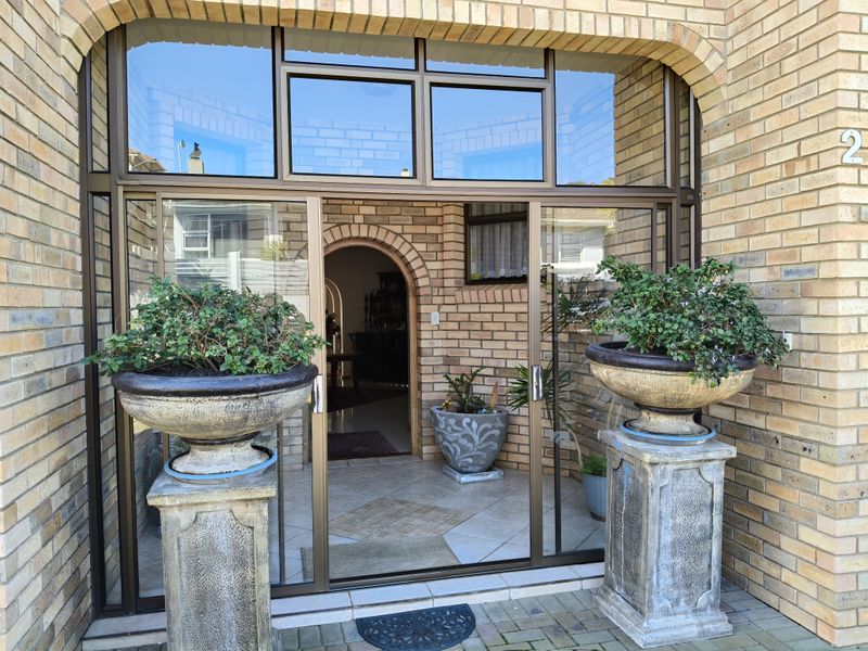 A welcoming front entrance featuring a brick facade, a large sliding glass door, and an arched interior doorway leading into the home.