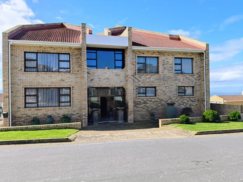 A well-maintained double-storey face brick residence featuring a tiled roof, paved driveway, and neat front lawn.