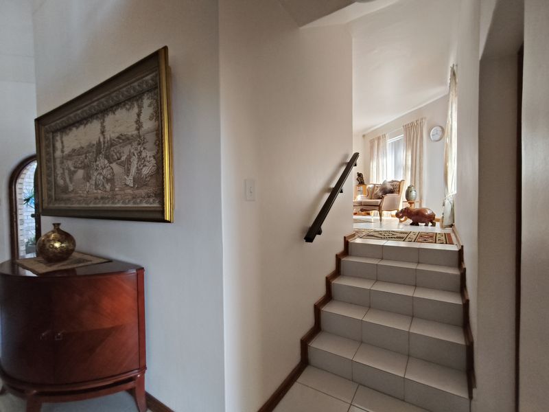 An inviting entryway featuring a tiled staircase with a handrail, leading into a bright, connected living space.