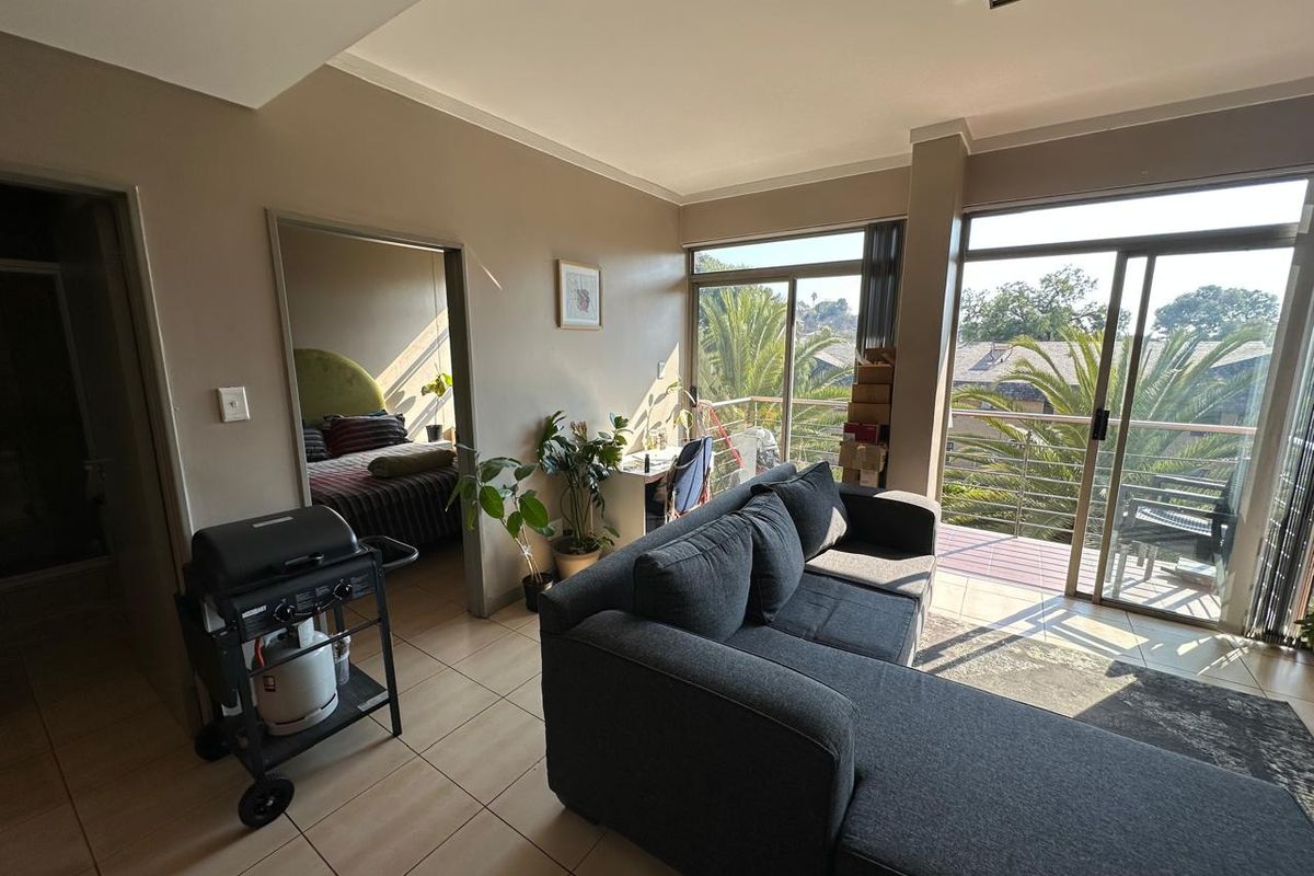 A living room featuring tiled flooring and large sliding glass doors that provide access to a balcony and natural light.