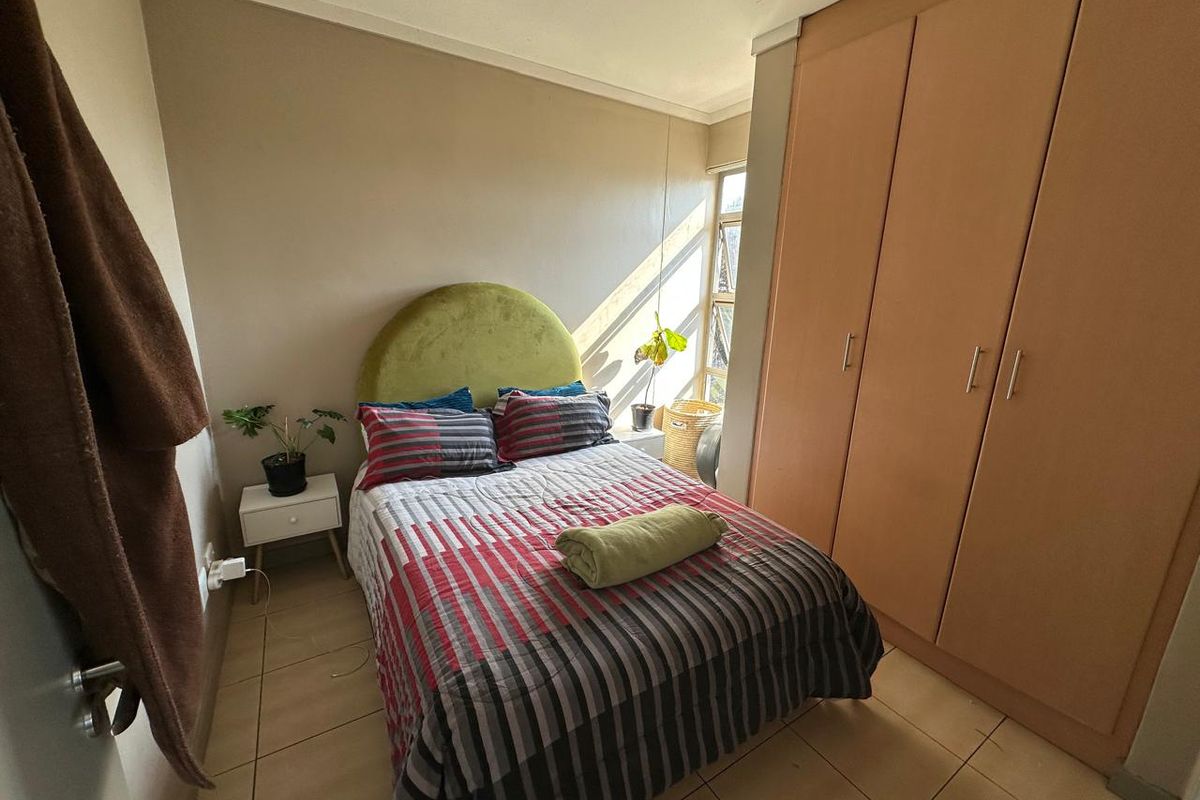 A compact bedroom featuring tiled flooring and built-in wooden cupboards, providing functional storage space.