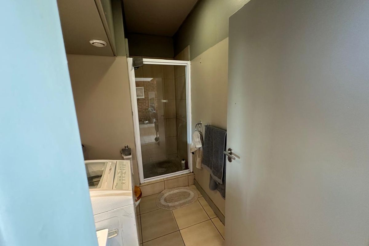 A functional bathroom featuring a glass-enclosed shower, tiled flooring, and neutral wall tones, providing a practical space with potential for cosmetic updates.