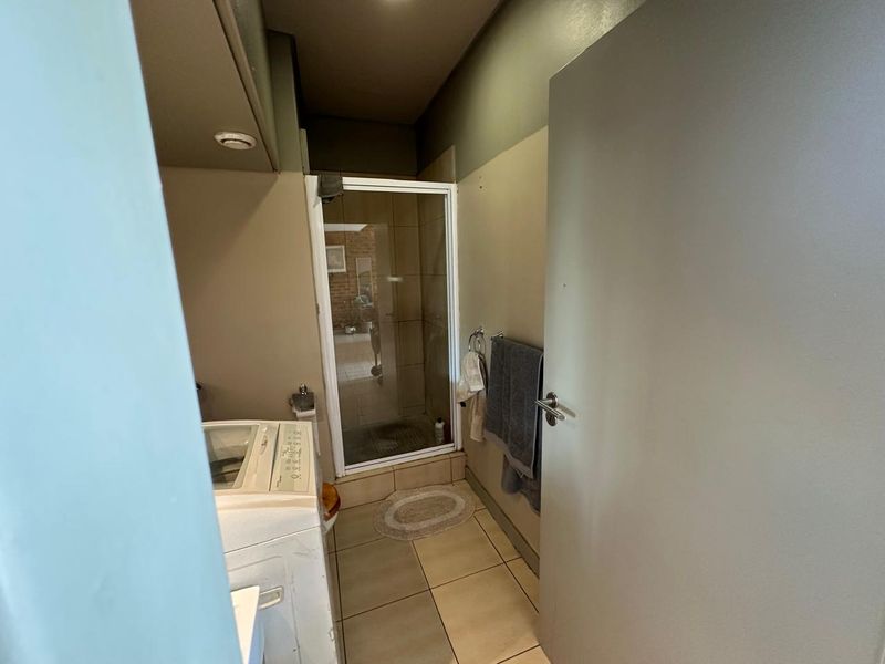 A functional bathroom featuring a glass-enclosed shower, tiled flooring, and neutral wall tones, providing a practical space with potential for cosmetic updates.