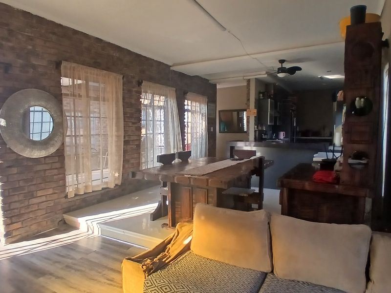 Open-plan living and dining area featuring exposed brick walls, tiled flooring, and a breakfast bar connecting to the kitchen space.