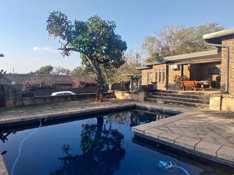 Outdoor pool area featuring a swimming pool with stone paving, brick exterior walls, and concrete steps leading to the house.