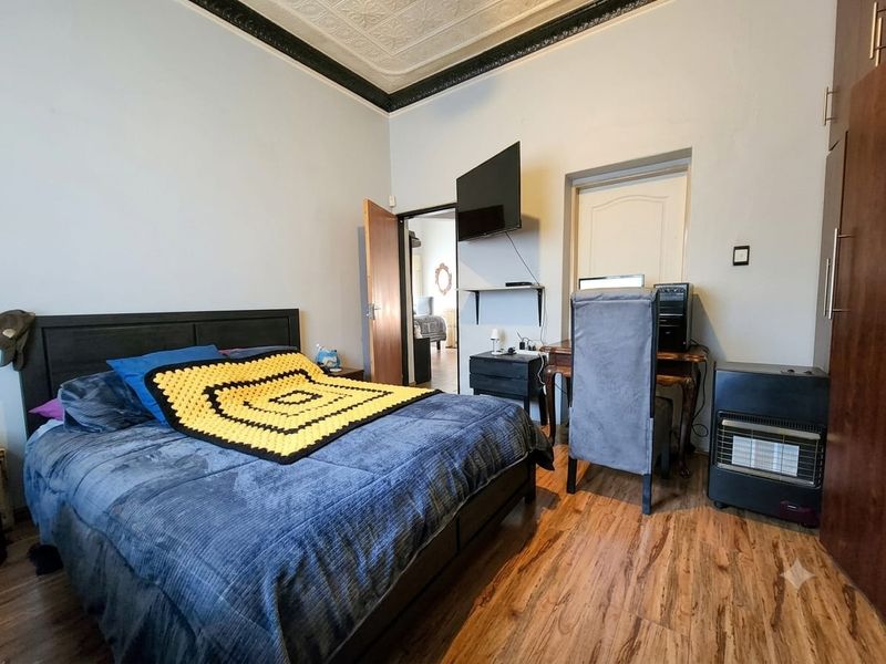 A bedroom featuring laminate flooring and a decorative ceiling, with a built-in wardrobe and access to an adjoining room.