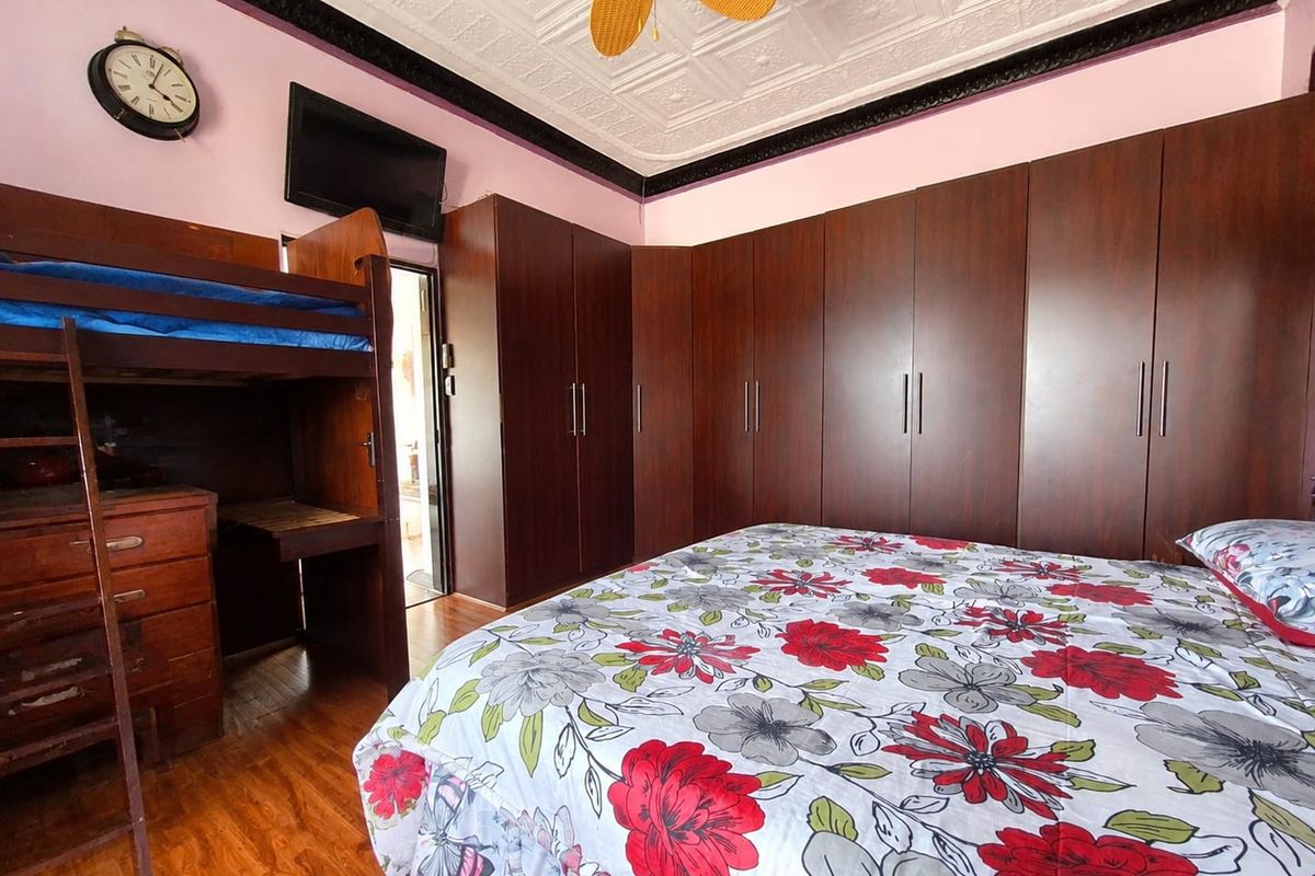 A bedroom featuring extensive built-in dark wood cabinetry, a decorative pressed metal ceiling, and a ceiling fan.