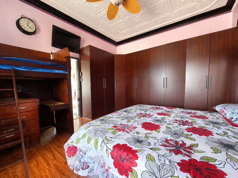 A bedroom featuring extensive built-in dark wood cabinetry, a decorative pressed metal ceiling, and a ceiling fan.