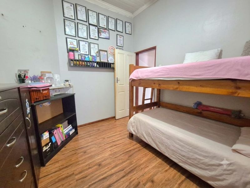 A bedroom featuring laminate flooring, a panel door, and coved ceiling details, providing a functional space for rest.