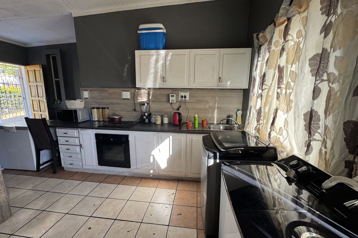 A functional kitchen featuring built-in cabinetry, an integrated oven and hob, tiled backsplash, and tiled flooring, offering potential for modernization and cosmetic updates.
