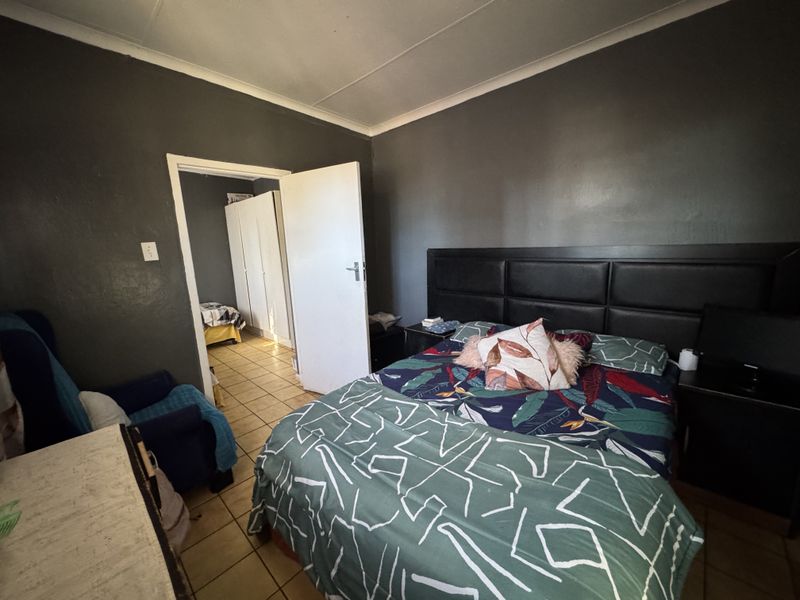 A bedroom featuring tiled flooring and coved ceilings, with an adjoining room visible through the doorway.