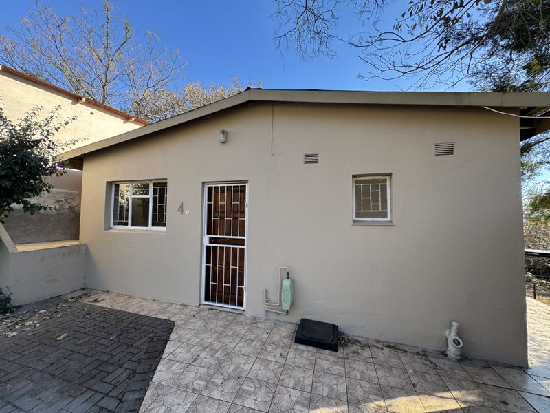 Front exterior view of the property featuring a tiled entrance area, security gate, and paved driveway access.