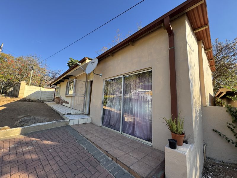 Rear exterior view of the property featuring a paved patio area, sliding glass door access, and a satellite dish installation.