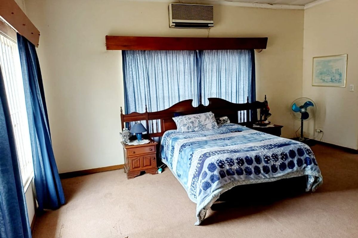 Spacious bedroom featuring wall-mounted air conditioning and carpeted flooring, offering a functional layout ready for cosmetic updates.