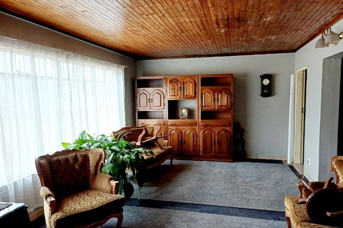 A living room featuring a warm timber tongue and groove ceiling and built-in wooden cabinetry, offering a traditional and cozy atmosphere.