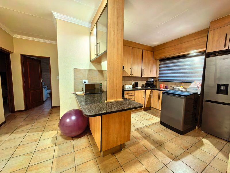 Functional kitchen featuring wood-finish cabinetry, granite countertops, a breakfast bar, and tiled flooring, providing a practical layout for daily meal preparation.