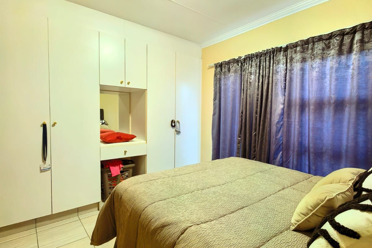 A bedroom featuring tiled flooring and extensive built-in cupboards with an integrated vanity mirror.