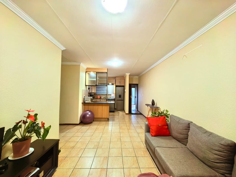 Open-plan living area featuring tiled flooring and a functional kitchen space with built-in cabinetry.
