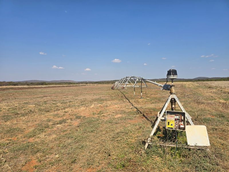 A large-scale center pivot irrigation system installed on open farmland, featuring a metal support structure and integrated control panel for agricultural water management.