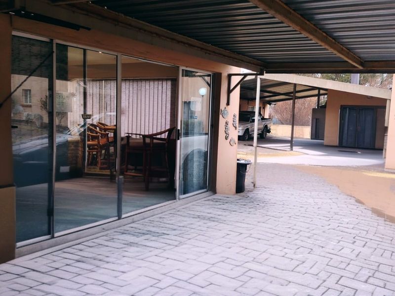 A covered patio area with sliding glass doors leading into the living space, featuring paved flooring and a metal carport structure.
