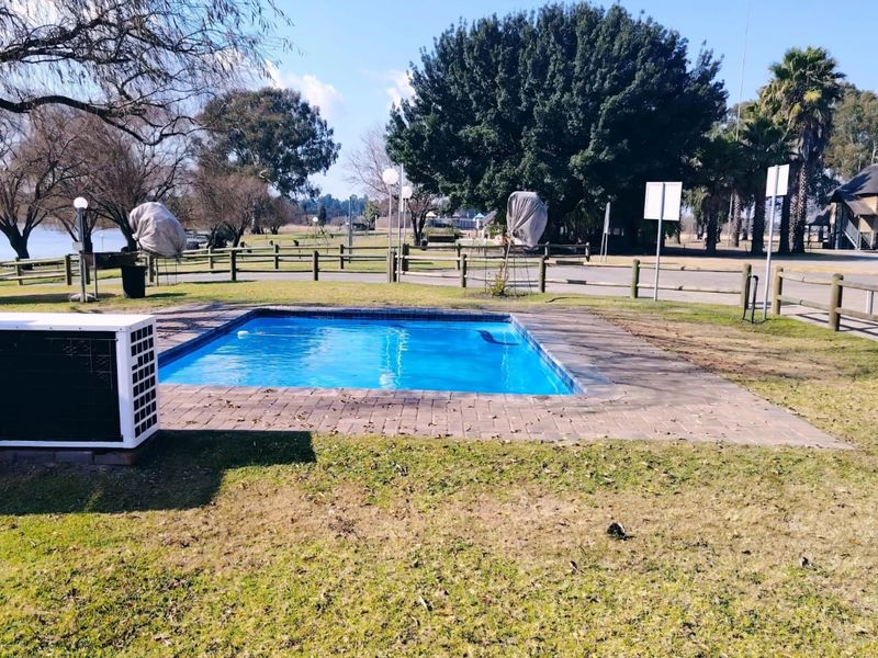 Outdoor swimming pool area featuring brick paving and timber fencing, set within a landscaped communal garden space.