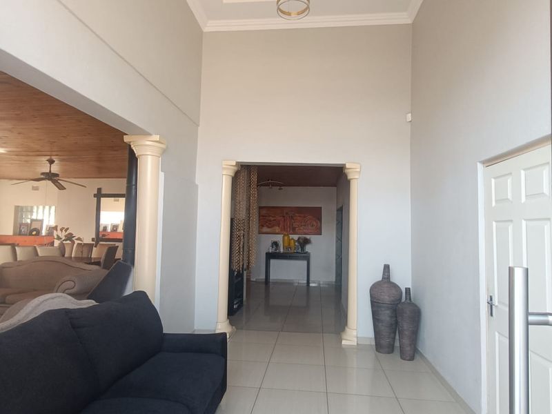 Spacious entrance hall featuring high ceilings with recessed lighting, decorative columns, and neutral tiled flooring leading into the main living areas.