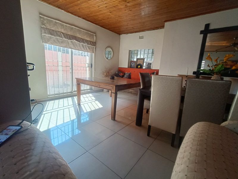 Dining area featuring tiled flooring, a timber tongue and groove ceiling, and a sliding glass door with security gate leading to the exterior.