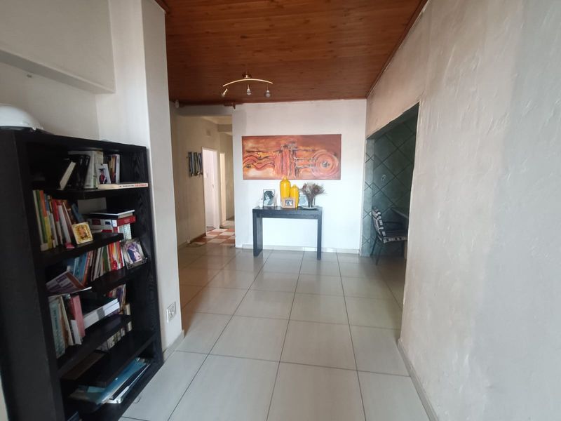 A spacious hallway featuring tiled flooring and a timber-paneled ceiling, providing access to adjacent rooms within the home.