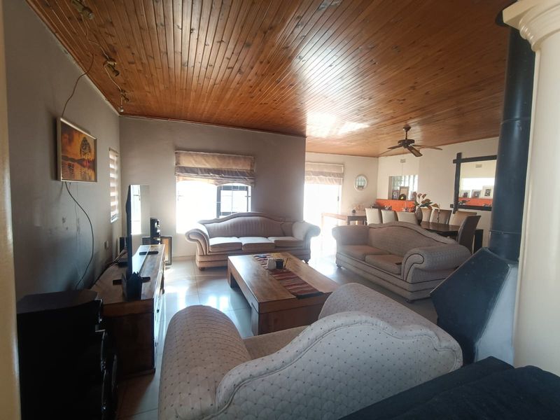 Spacious open-plan living and dining area featuring a timber tongue and groove ceiling, tiled flooring, and a prominent freestanding fireplace.