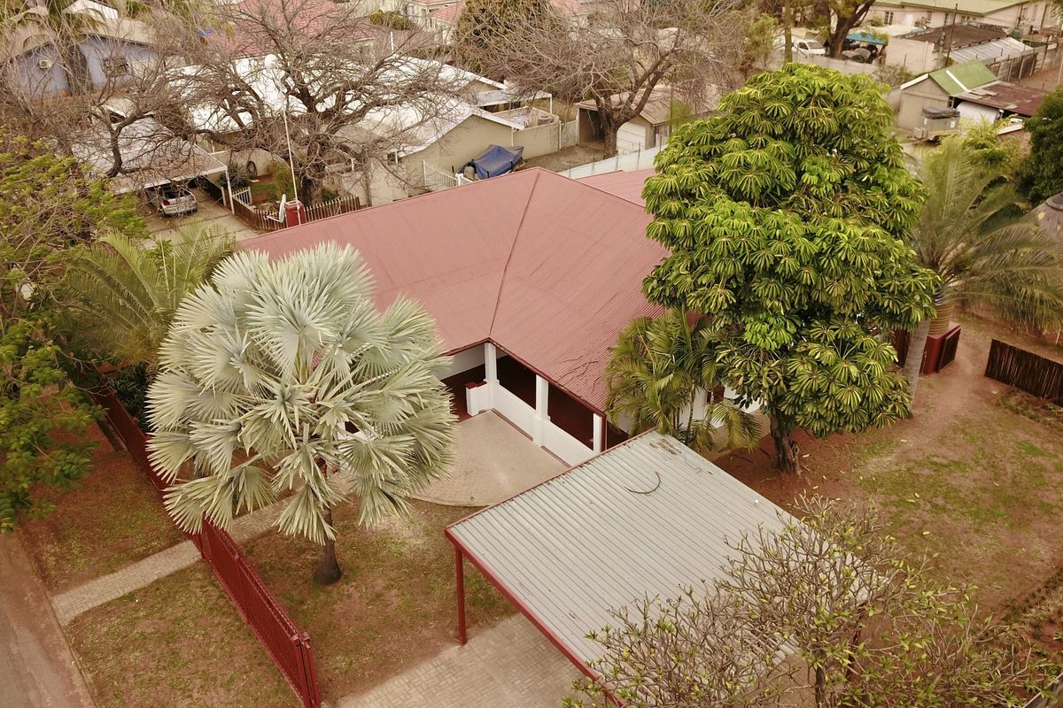 Aerial view of the property showing the main dwelling with a metal roof, a detached carport, and established garden landscaping.
