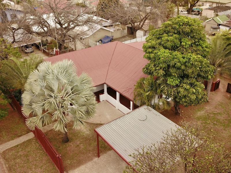 Aerial view of the property showing the main dwelling with a metal roof, a detached carport, and established garden landscaping.