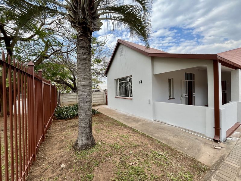 Front view of a single-story house featuring a covered porch, metal security fencing, and a concrete walkway leading to the entrance.