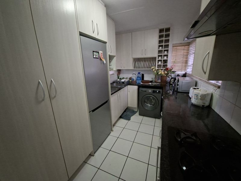 Compact kitchen featuring light-toned built-in cabinetry, dark granite countertops, ceramic tile flooring, and integrated storage solutions including a wine rack.