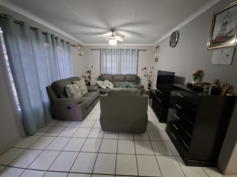 A comfortable living room featuring tiled flooring, a ceiling fan, and neutral wall finishes, providing a functional and well-maintained space.