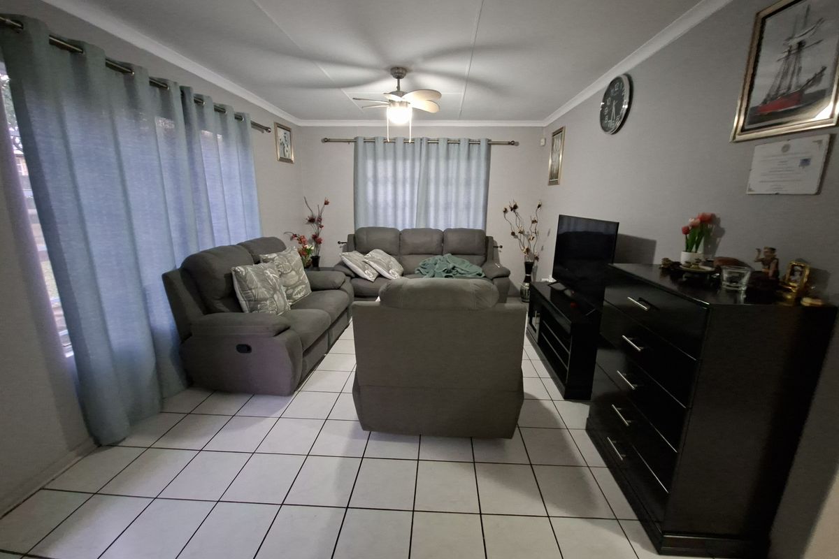 A comfortable living room featuring tiled flooring, a ceiling fan, and neutral wall finishes, providing a functional and well-maintained space.