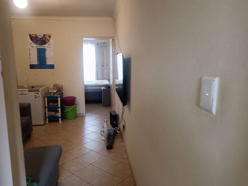 A living area featuring tiled flooring and neutral walls, providing a functional space with direct access to an adjacent bedroom.