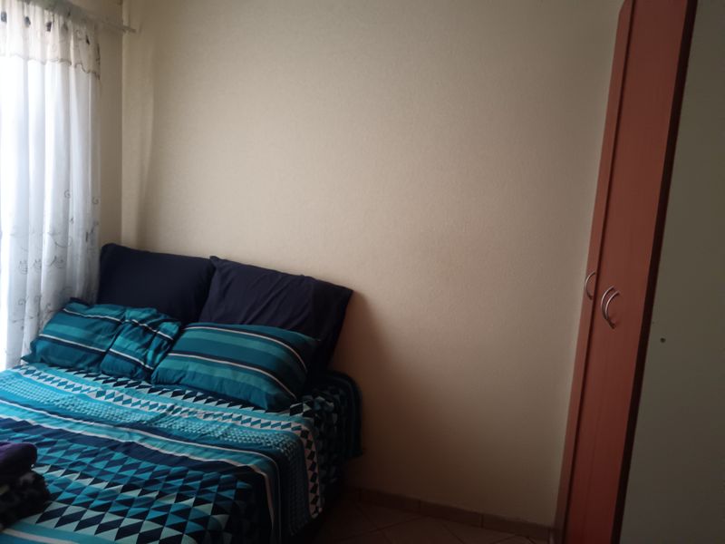 A bedroom featuring tiled flooring and a built-in wardrobe, providing functional storage space within the room.