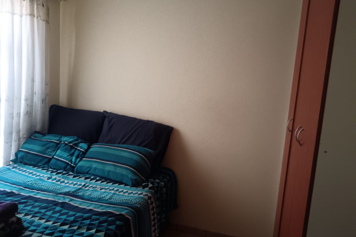 A bedroom featuring tiled flooring and a built-in wardrobe, providing functional storage space within the room.