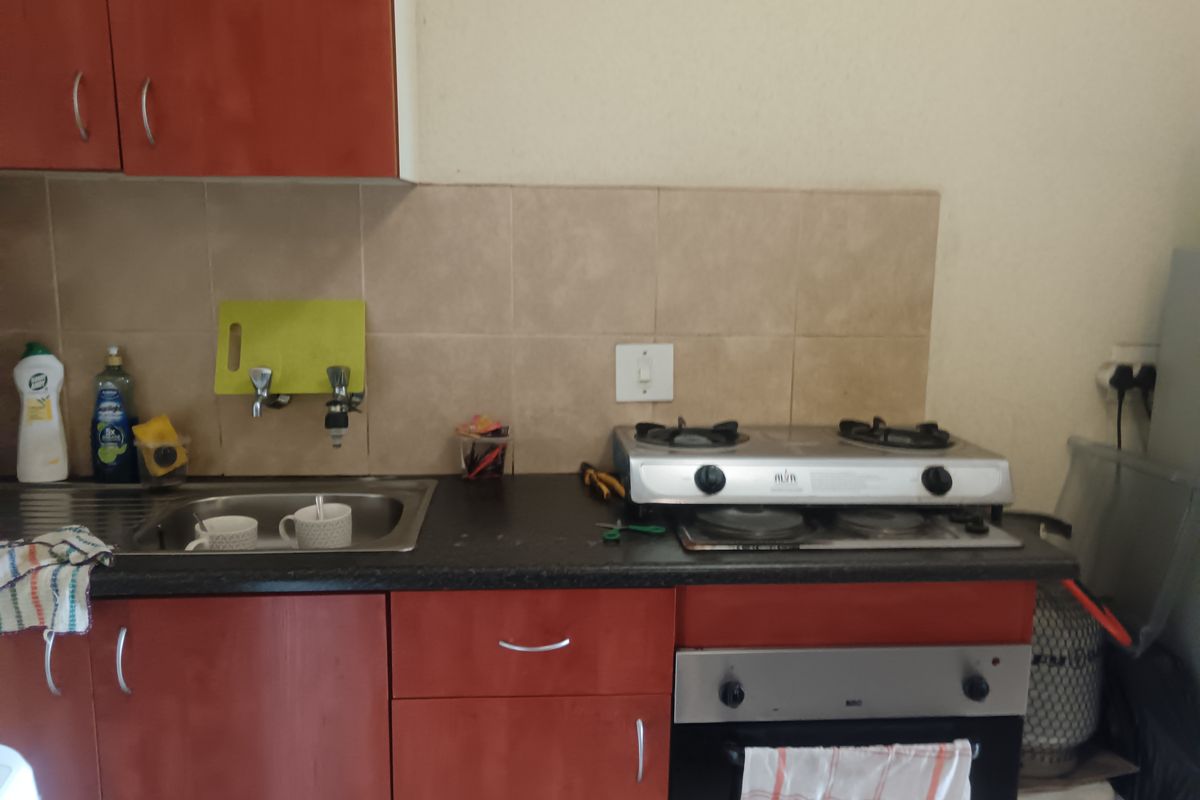 A functional kitchen featuring laminate cabinetry, a stainless steel sink, tiled backsplash, and a built-in gas hob with oven.