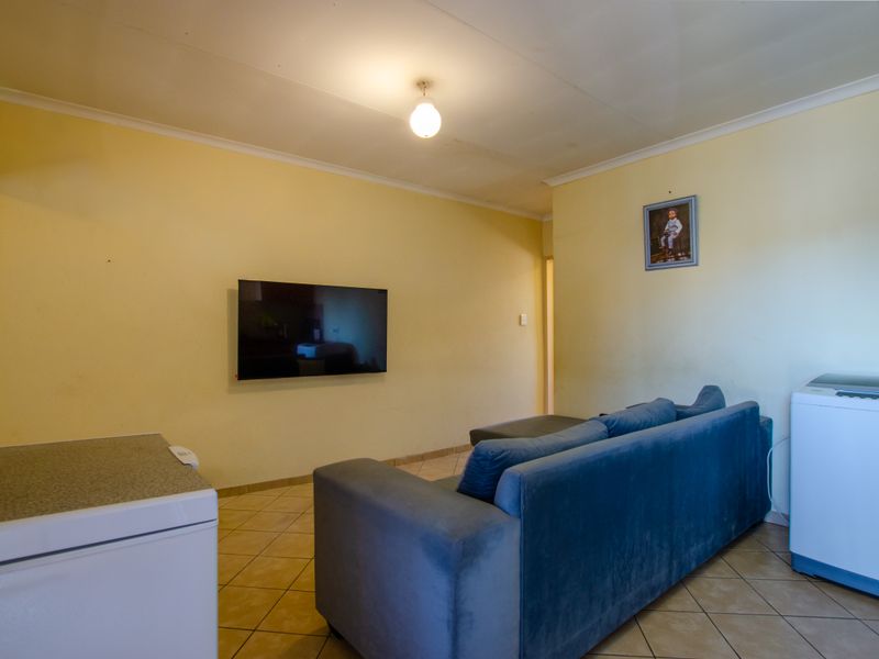 A living area featuring tiled flooring and cove cornicing, currently used as a multi-purpose space.