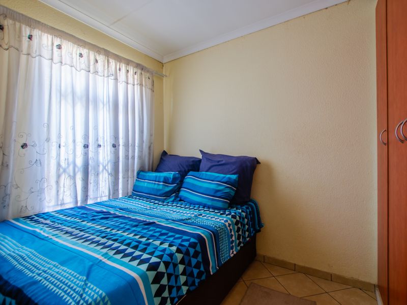 A functional bedroom featuring tiled flooring and a built-in wardrobe, providing essential storage space within the townhouse.