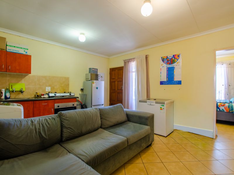 Open plan living area featuring a compact kitchen with built-in cabinetry, tiled flooring, and direct access to an adjacent bedroom.