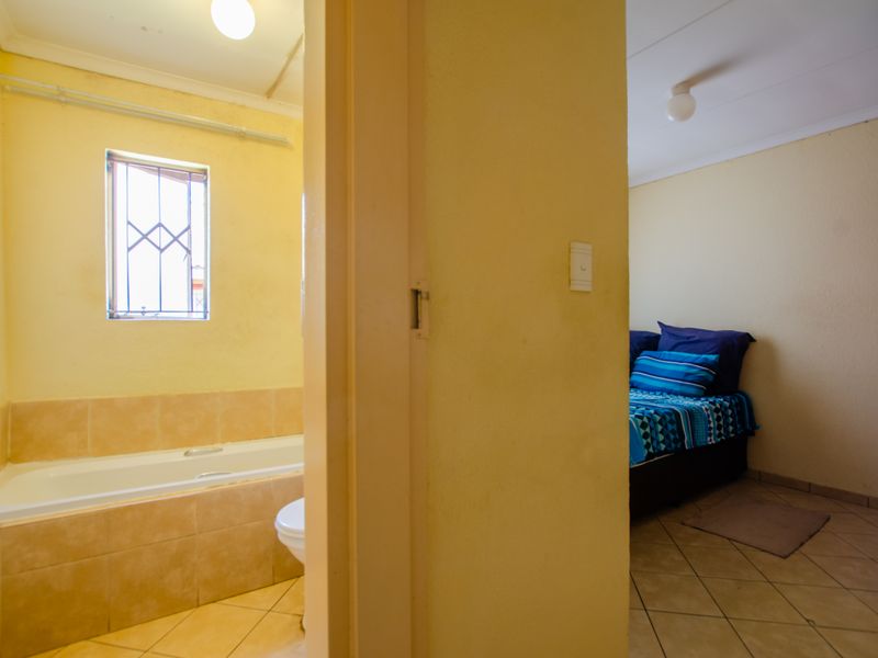 A view from a bedroom into a dated bathroom featuring a built-in bathtub and ceramic floor tiles.
