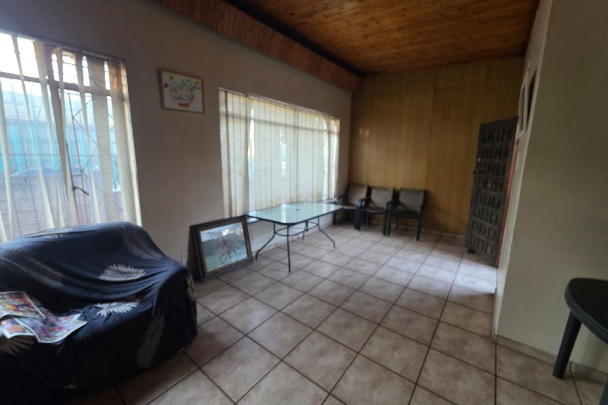 Living area featuring tiled flooring, timber ceiling, and wood-paneled walls, offering a dated aesthetic with potential for modernization.